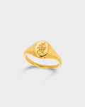 A gold signet ring featuring an engraved floral motif on its flat top.