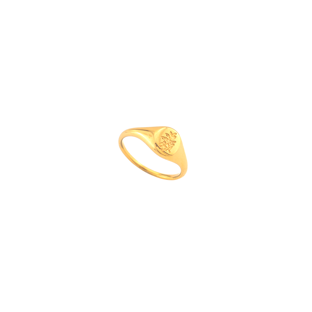 A gold signet ring featuring an engraved floral motif on its flat top.