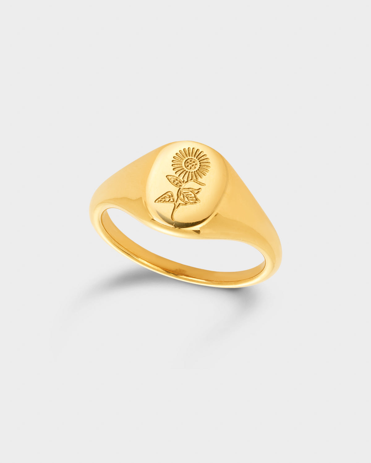 A polished yellow gold signet ring featuring an engraved rose motif on its oval face.