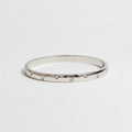 One slim silver bangle bracelets with small clear rhinestones.