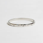 One slim silver bangle bracelets with small clear rhinestones.