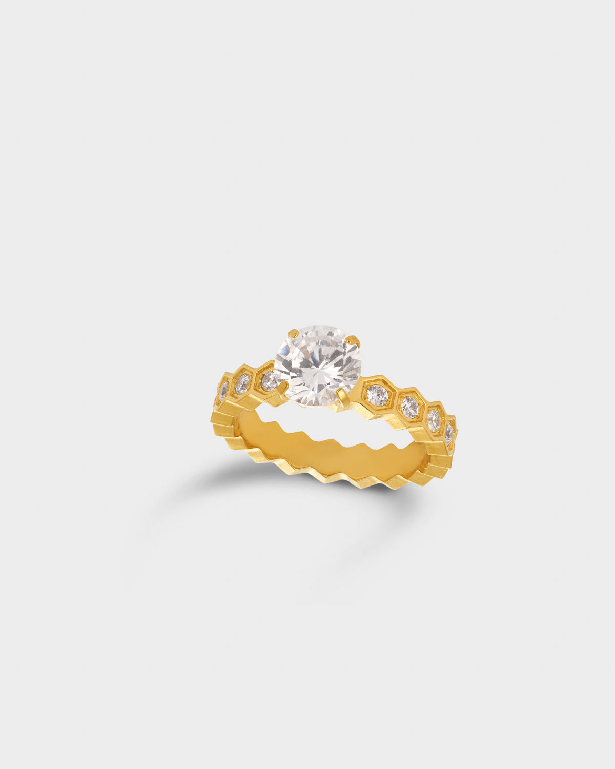A yellow gold eternity-style ring featuring a large round clear center stone and smaller round stones set along a wavy band.