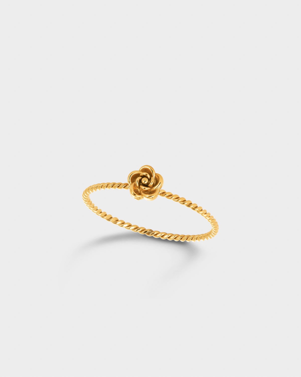 A delicate gold ring featuring a twisted rope-style band and a small rose-shaped flower at the top.