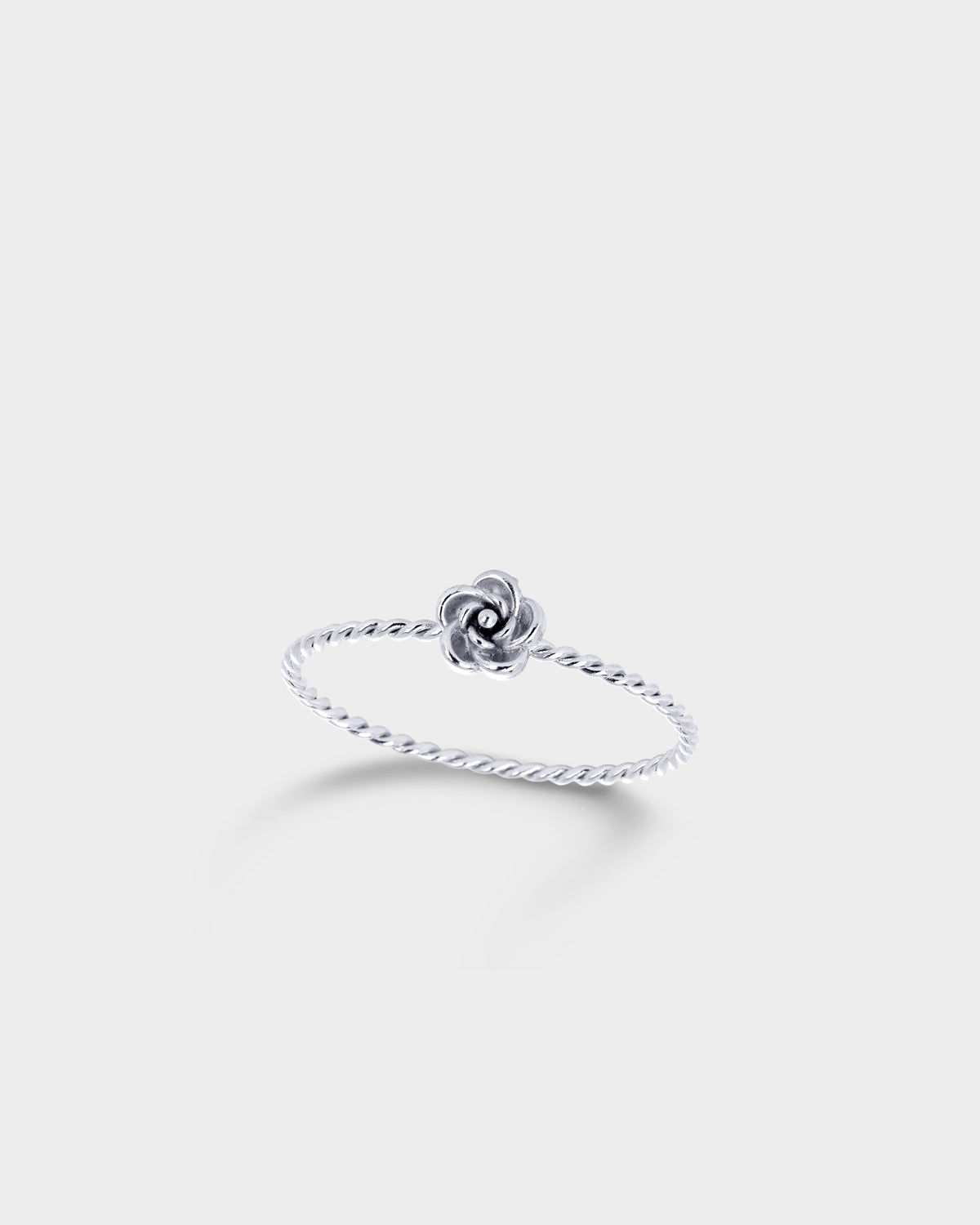 A delicate silver ring featuring a twisted band and a small central flower-like charm.
