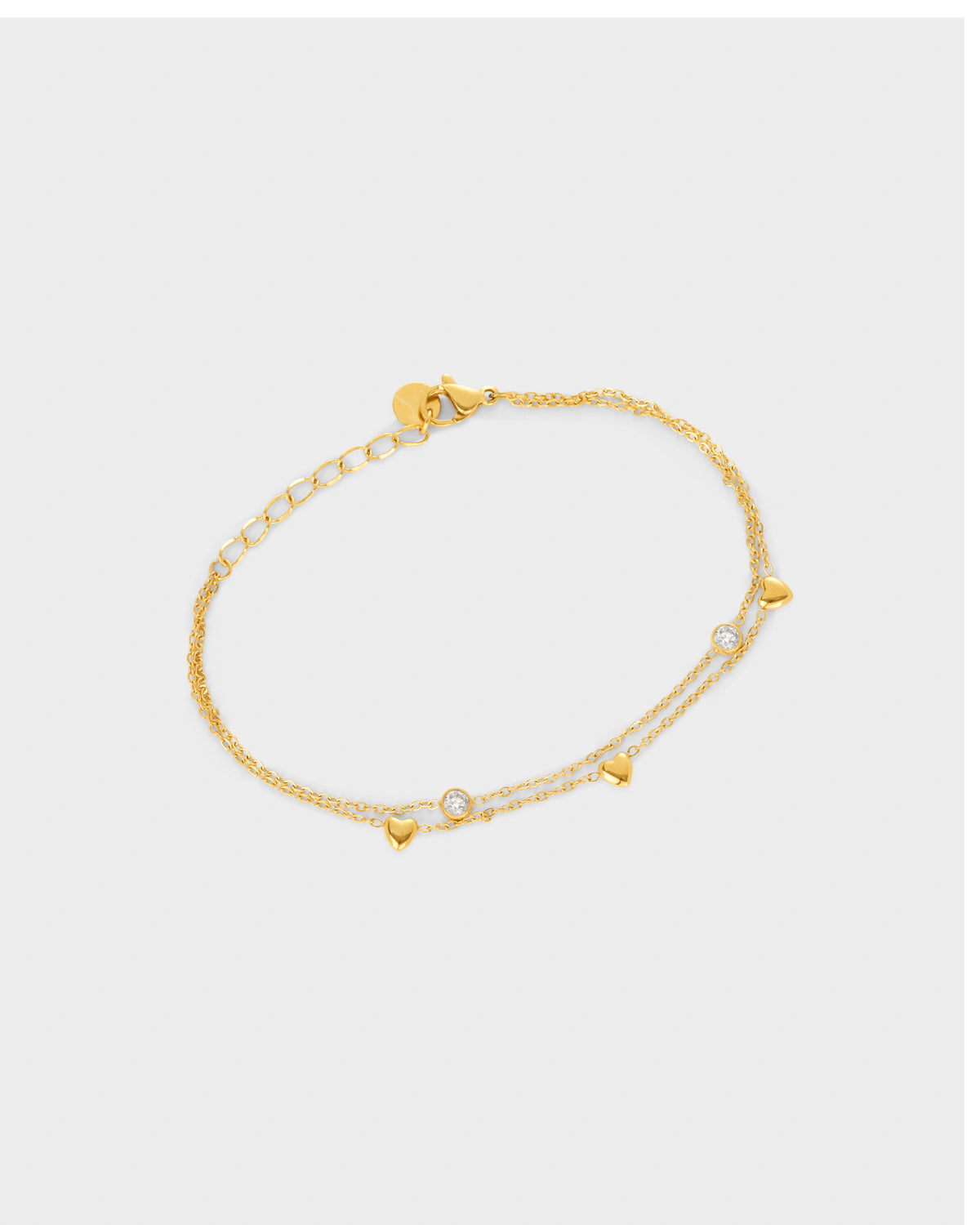 A delicate gold chain double layered bracelet featuring small dangling circle and heart charms.