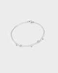 A delicate silver chain double layered bracelet featuring small dangling circle and heart charms.