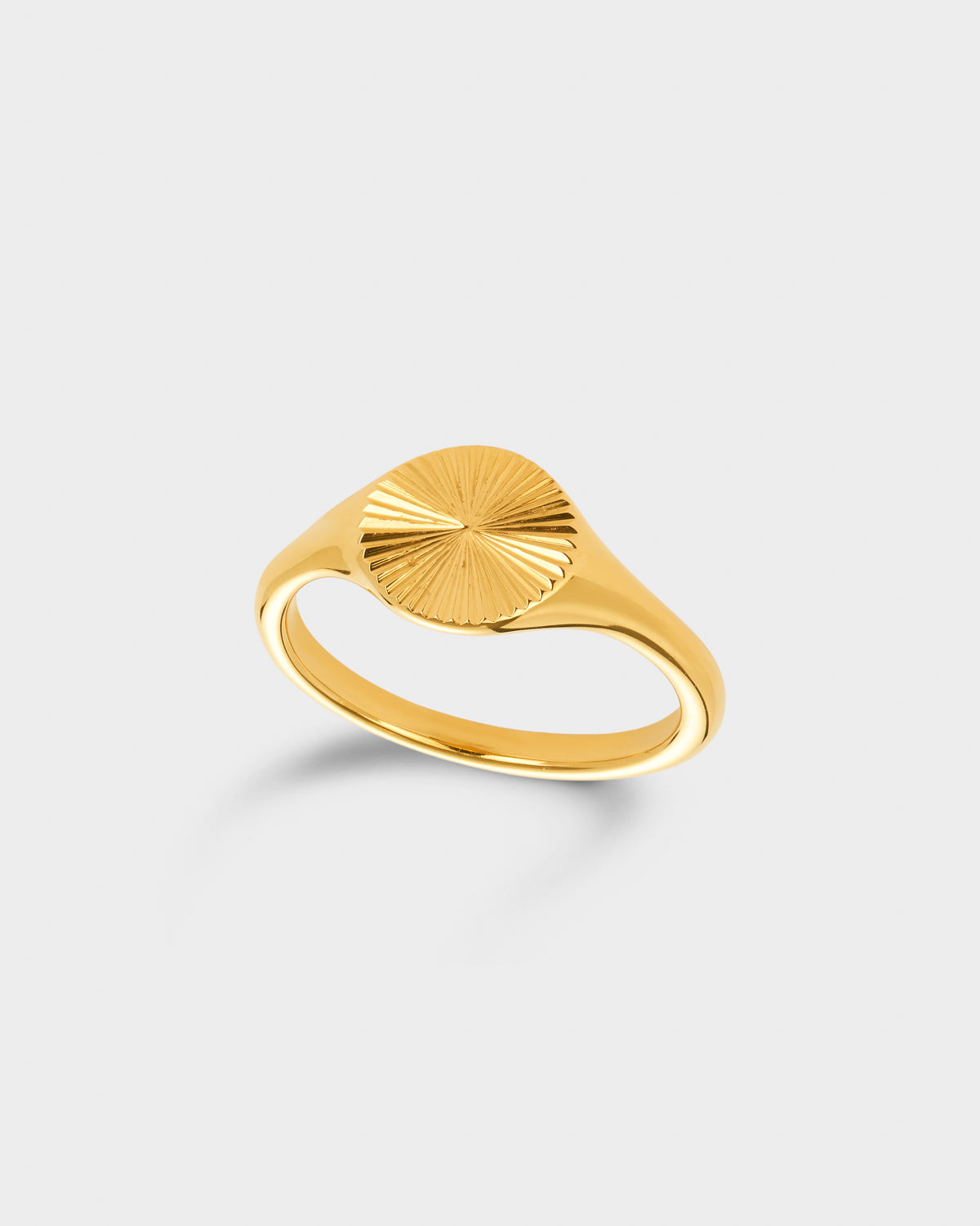 A gold signet ring with a textured, sunburst-patterned top